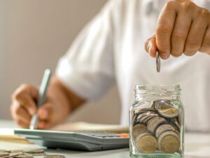 Jak oszczędzać na co dzień – kobieta planująca budżet z słoikiem oszczędności